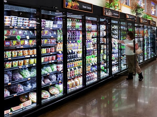 An image of a lady using refrigerated display case